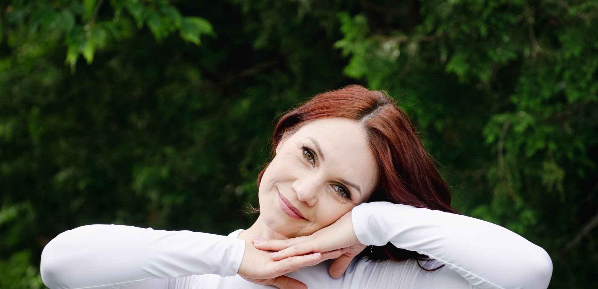 Anna resting her chin on her hands, smiling warmly, outdoors