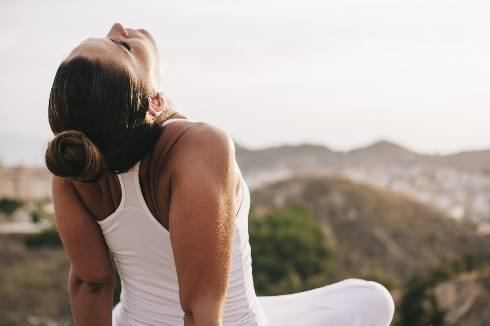 A woman with eyes closed, tilting her face toward the sunlight, a quiet moment
